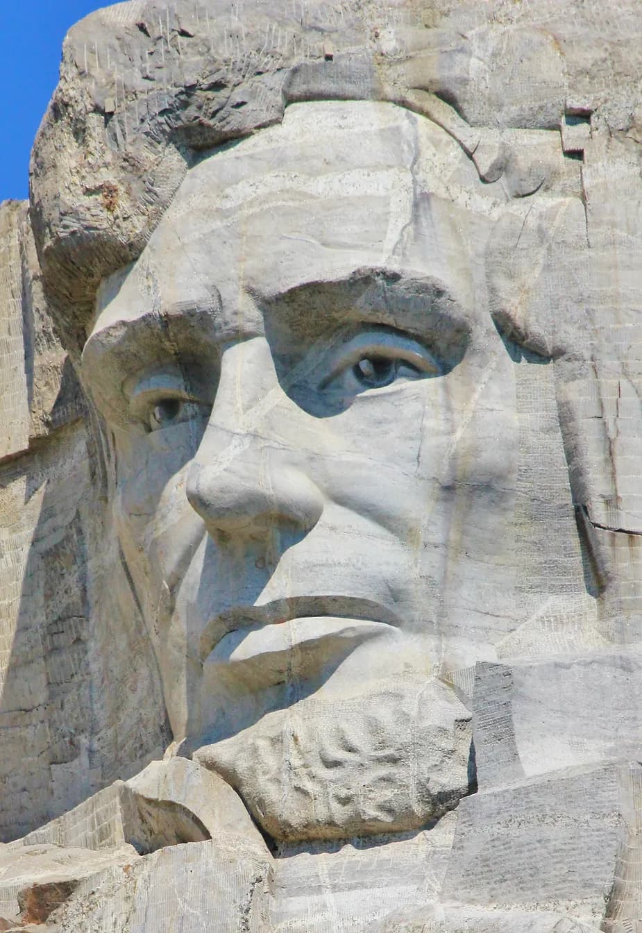 Imagem do rosto de Lincoln no Monte Rushmore: Close do rosto de Abraham Lincoln esculpido no Monte Rushmore, destacando seus traços imponentes.