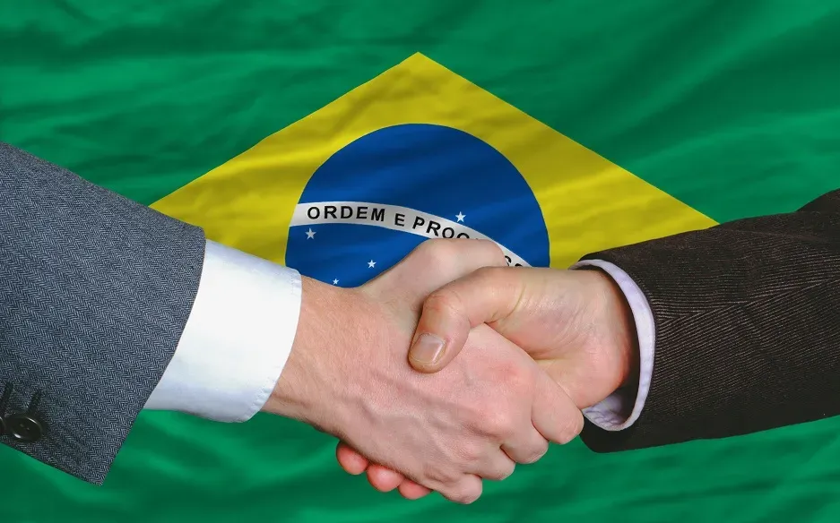 Profissionais brasileiros se cumprimentando em uma reunião de negócios, ilustrando a importância das relações pessoais.